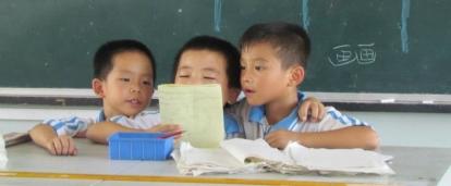 Three young boys read aloud during a class taught by a Childcare volunteer at a kindergarten in China. A Projects Abroad volunteer working with children in China listens to young boys reading aloud to improve their reading skills.